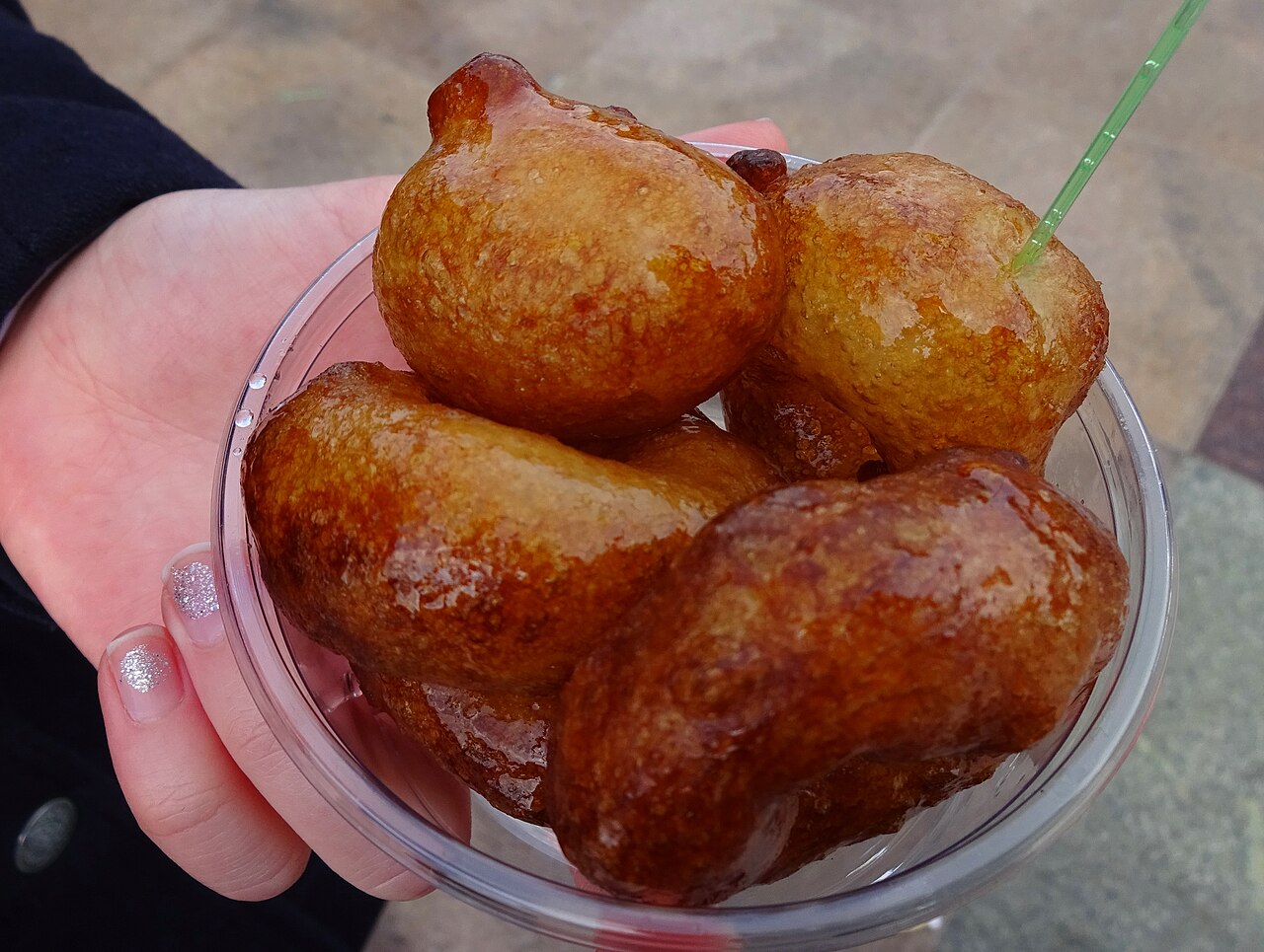 Golden fried awameh dough balls glistening with syrup in a clear cup